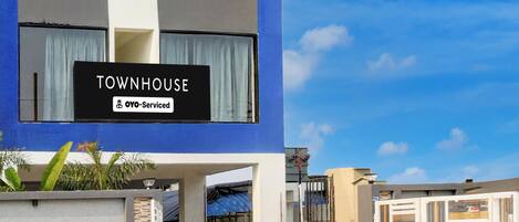 A modern townhouse with a sign indicating it is serviced by OYO.