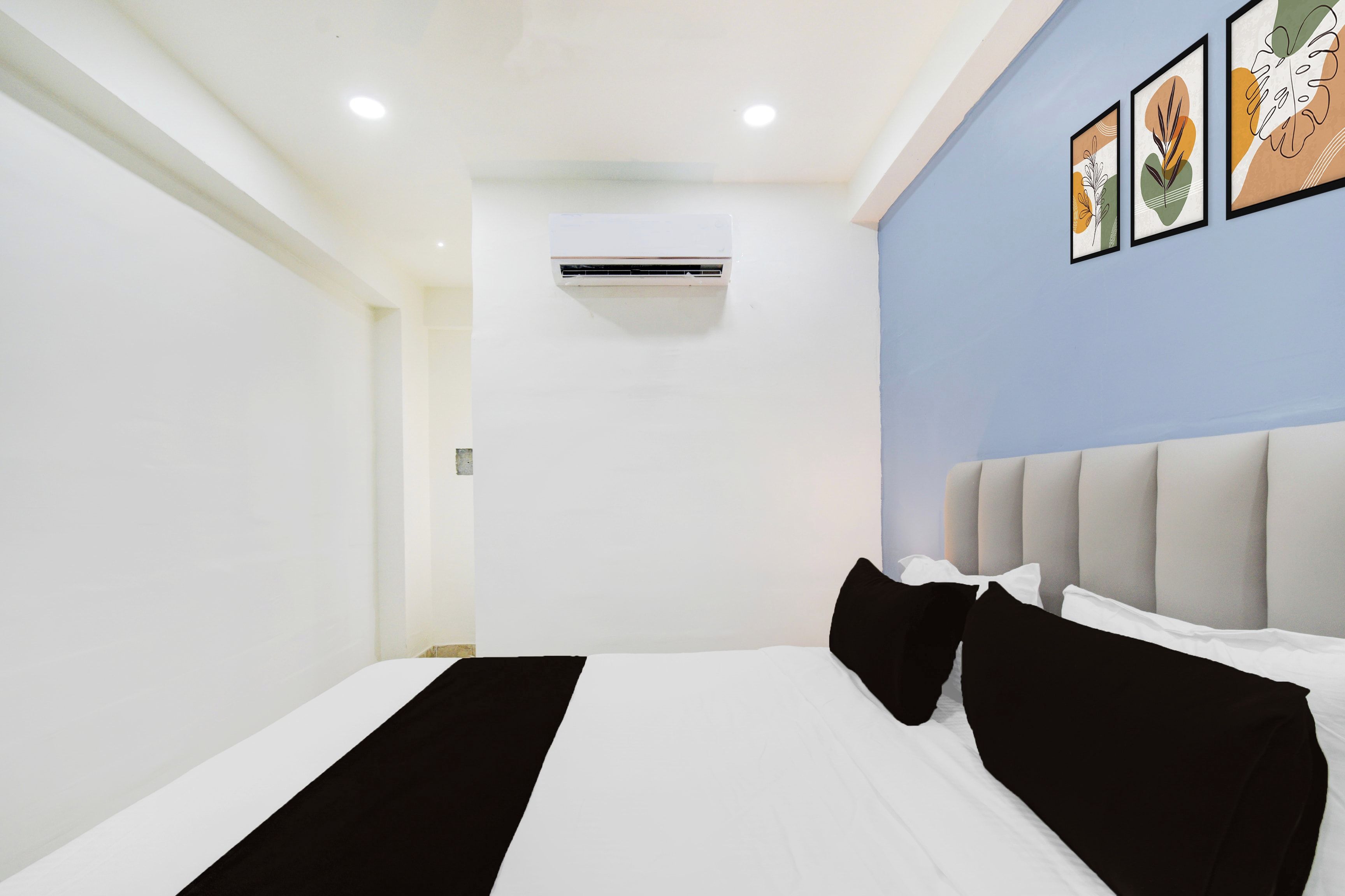 A hotel room with a bed, a headboard, and wall-mounted air conditioning unit.