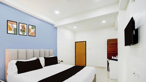 Quarto de hotel com cama, televisão e obras de arte na parede.