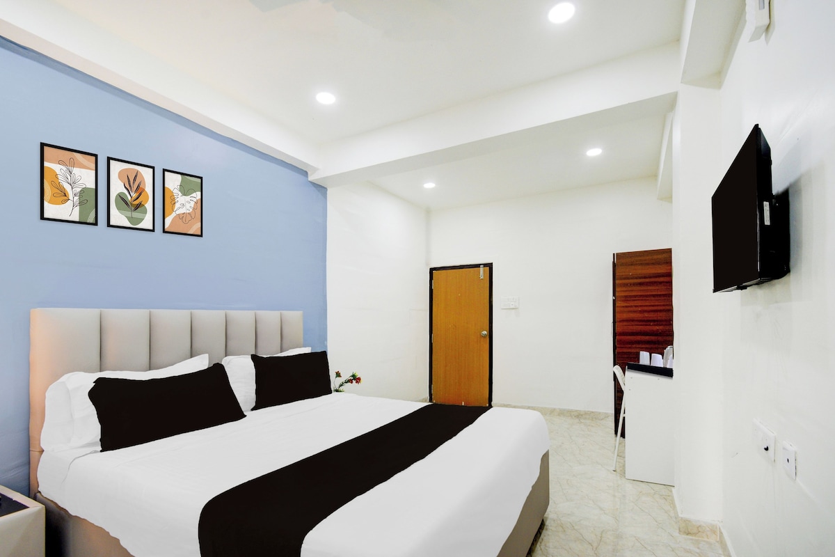 A hotel room with a bed, a television, and artwork on the wall.
