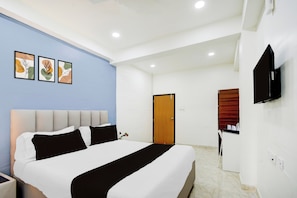 A hotel room with a bed, a television, and artwork on the wall. - Townhouse Nagole Metro Station (Hyderabad)