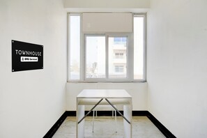 A room with a white table and a window. There is a sign on the wall that reads 'TOWNHOUSE OYO-Serviced'.