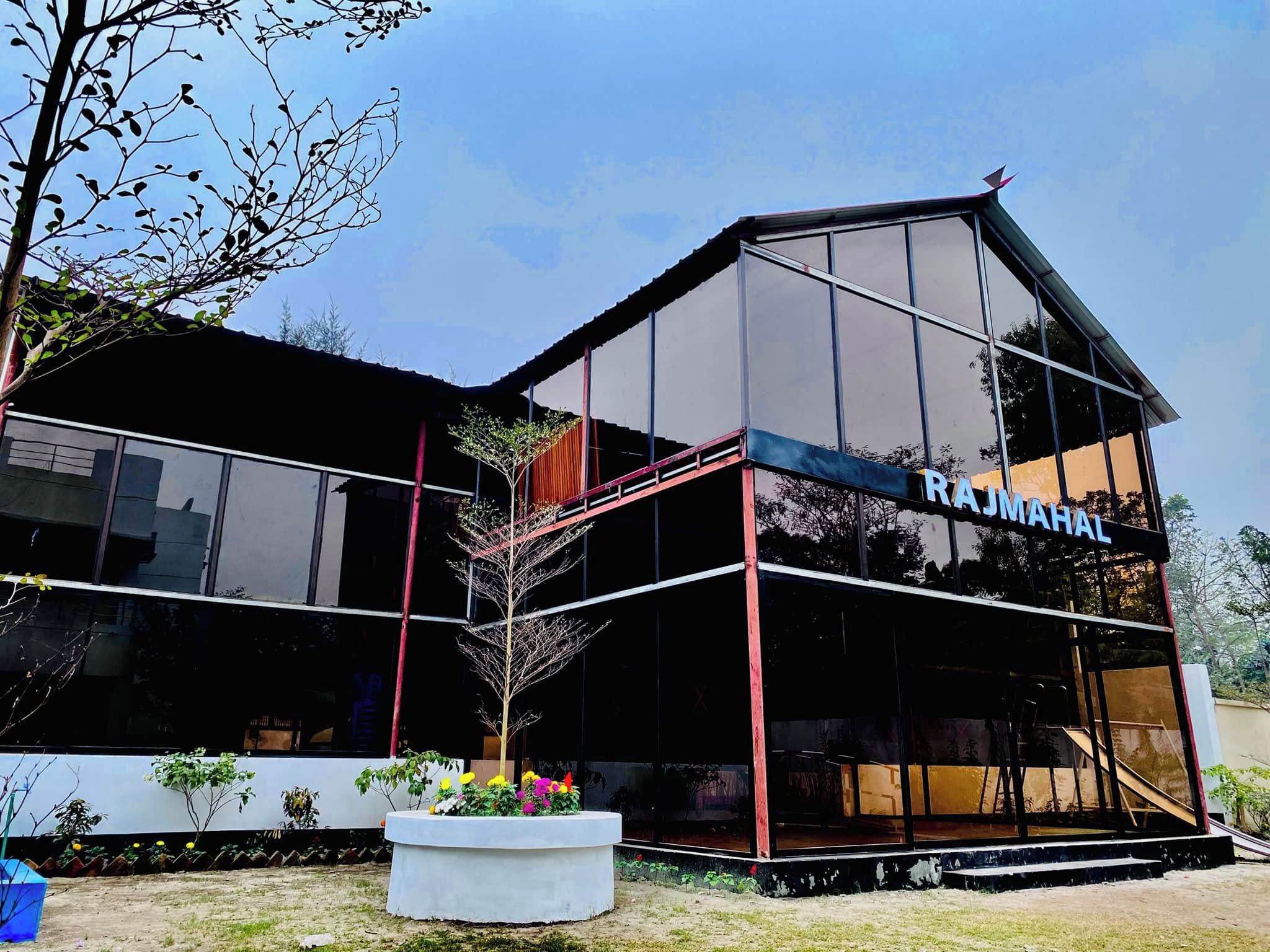 A modern building with a glass facade and the name 'RAJMAHAL' on the side.