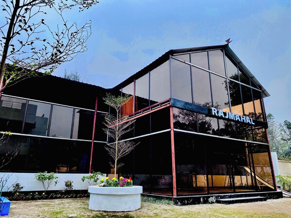 A modern building with a glass facade and the name 'RAJMAHAL' on the side.