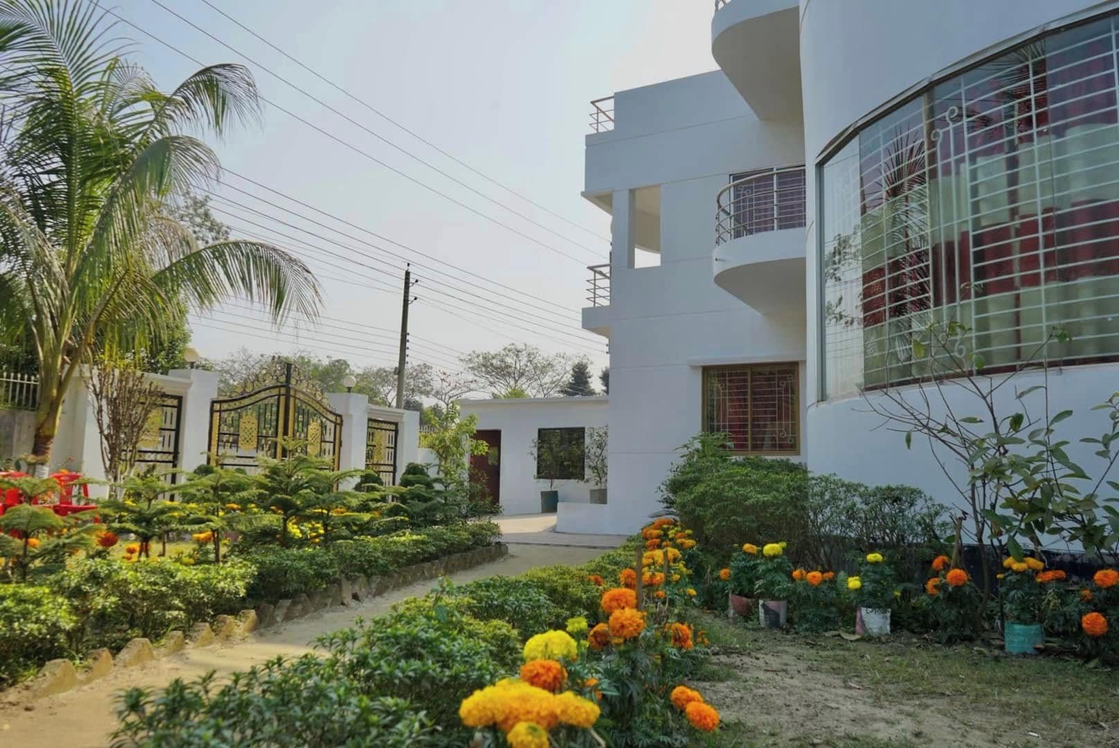 Un edificio moderno con fachada blanca, varios balcones y un jardín con flores de cempasúchil.