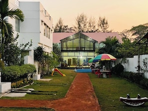 A modern building with a glass facade, a swimming pool, and outdoor seating.