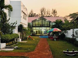 Um edifício moderno com fachada de vidro, piscina e área de estar externa.