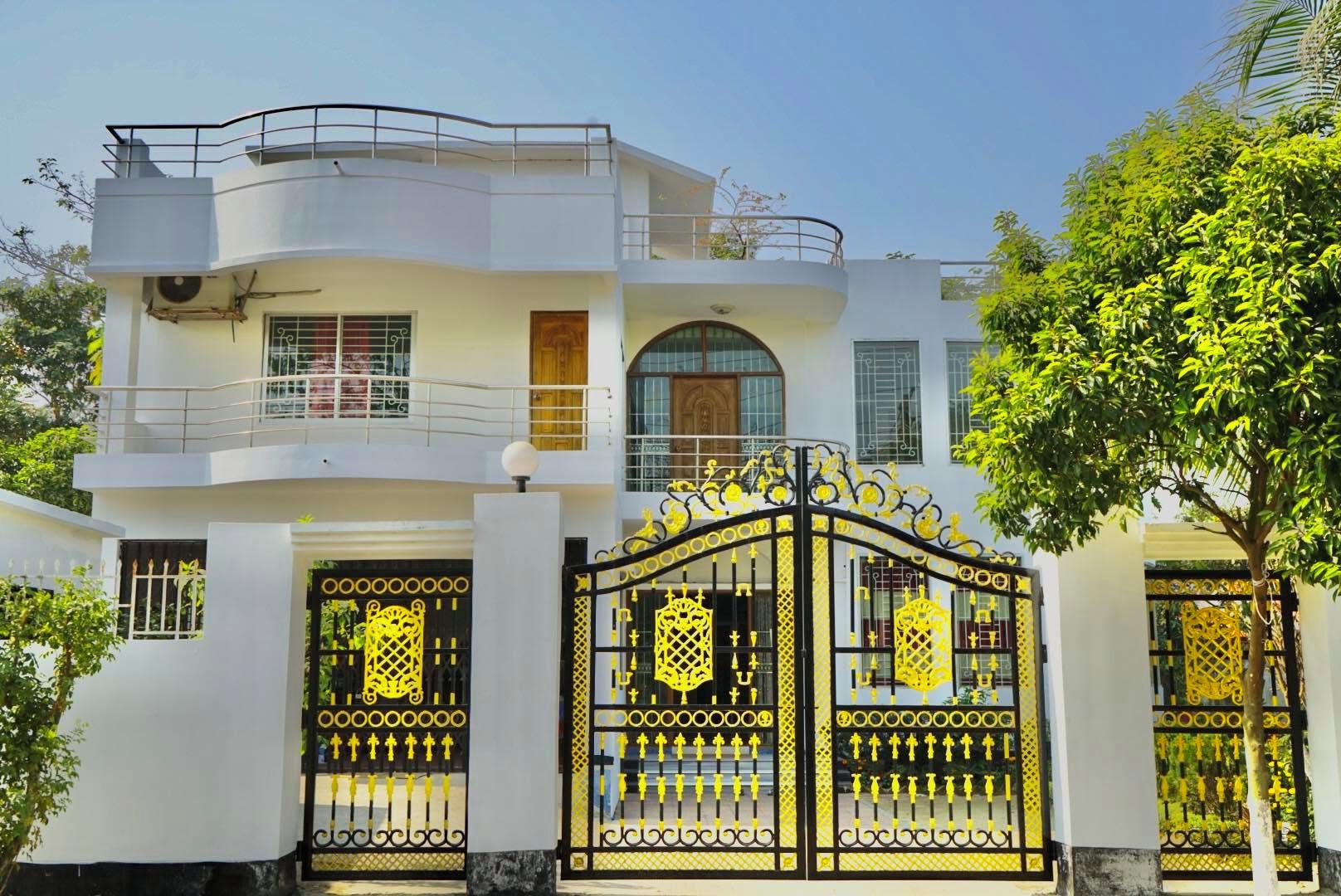 A two-story building with a gated entrance, balconies, and a tree in the foreground.