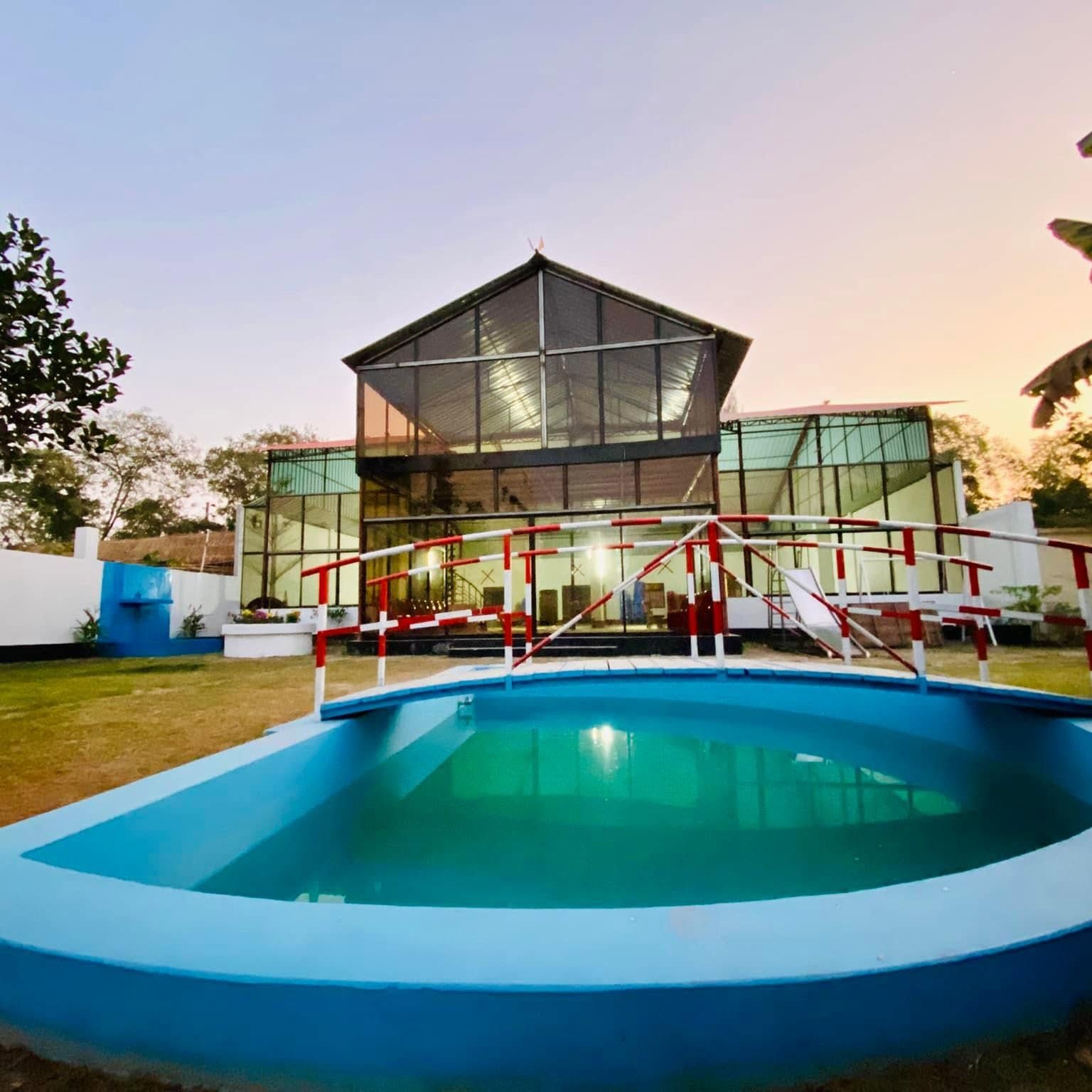 A modern building with a large glass facade and a swimming pool in the foreground.
