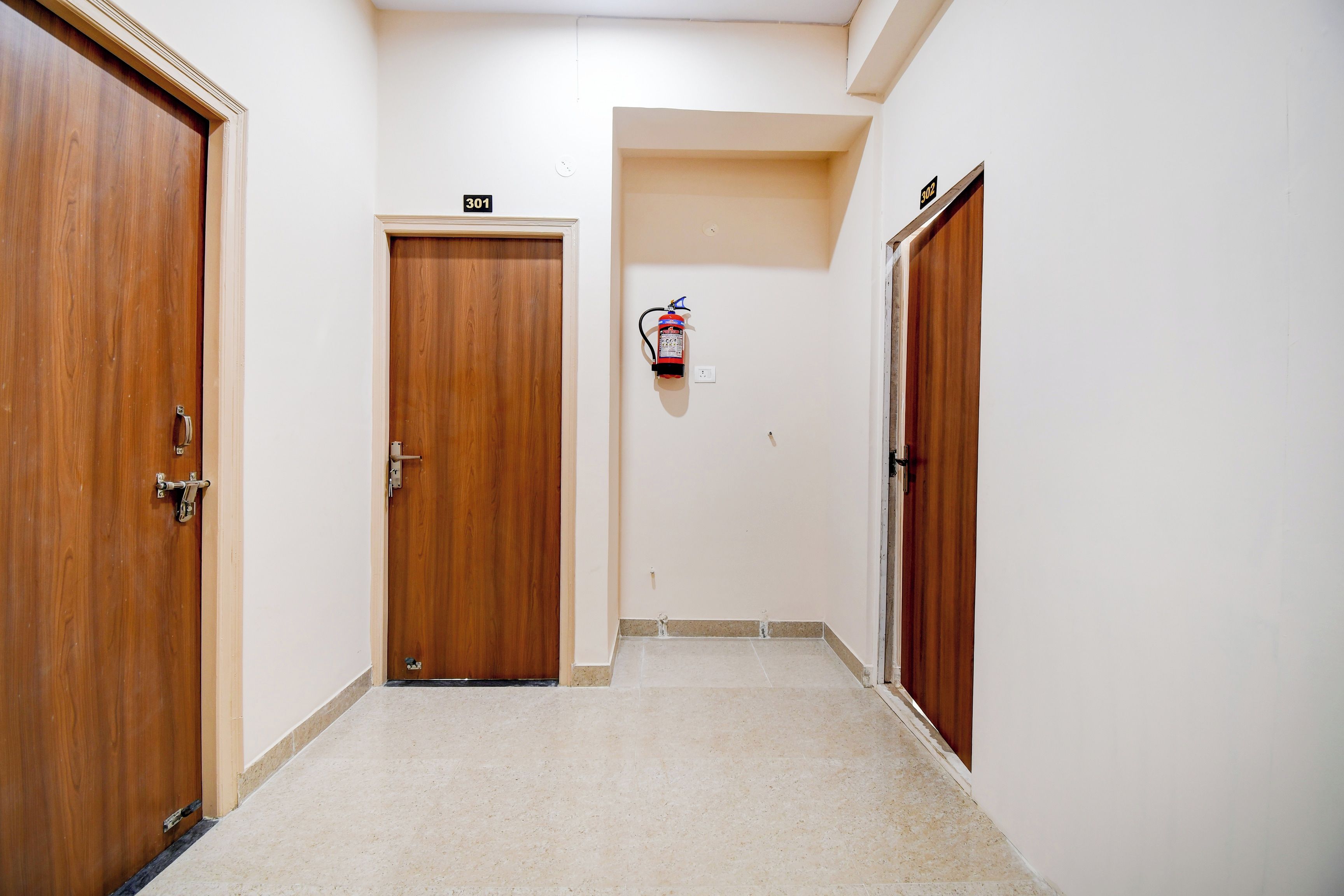 Un pasillo con puertas de madera, con los números 301 y 302, y un extintor de incendios sujeto a la pared.