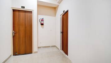 Un pasillo con dos puertas de madera, cada una con un número, y un extintor colgado en la pared.