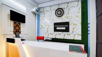 A reception desk with a clock, a sign indicating 'TOWNHOUSE Company-Serviced', and a framed picture on the wall.