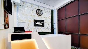 A reception desk with a marble wall, a clock, and a sign indicating it's a company-serviced area. - Super Townhouse Kumhrar Archeological (Patna)