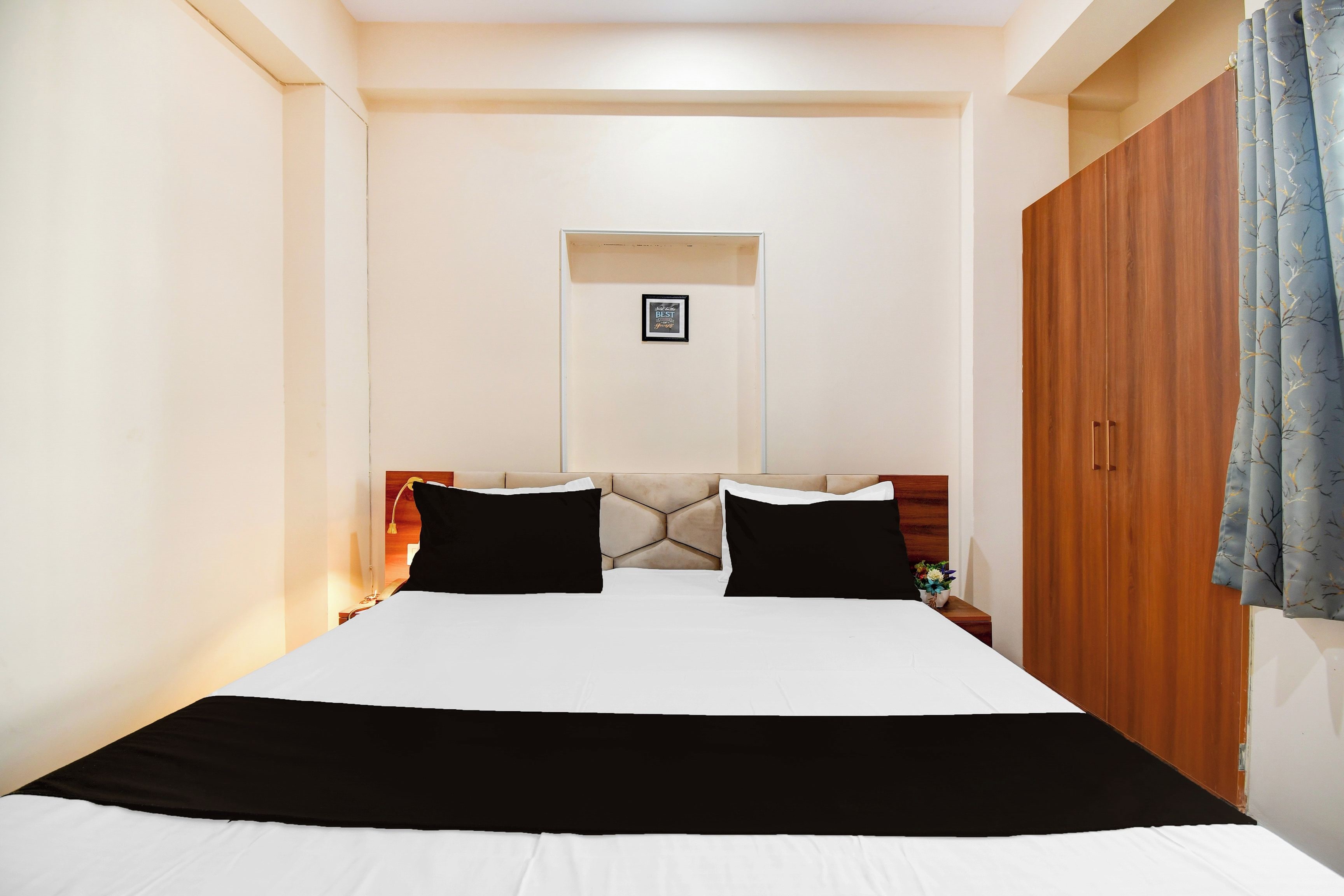 Un dormitorio con cama, un armario de madera, una mesita de noche y un cuadro en la pared.