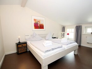 A hotel room with a large bed, a bedside table with a lamp, a framed picture on the wall, and a window with curtains. - Brandgans at Susanne-fischer Weg 43 (Wyk auf Foehr)