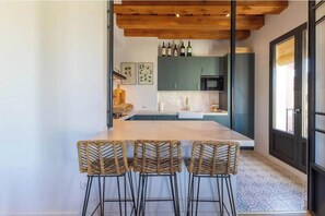 A kitchen with a large island, bar stools, and a wooden ceiling.
