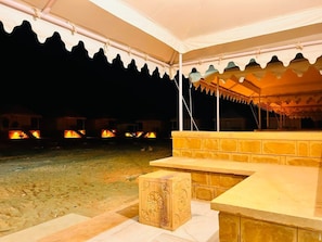 A tented outdoor area with a stone bench and a wooden block. - Jaisalmer Sand Dunes Luxury Camp and Resort (Jaisalmer)