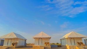 Three white tents with a peaked roof, each with a door and a small porch area. - Jaisalmer Sand Dunes Luxury Camp and Resort (Jaisalmer)
