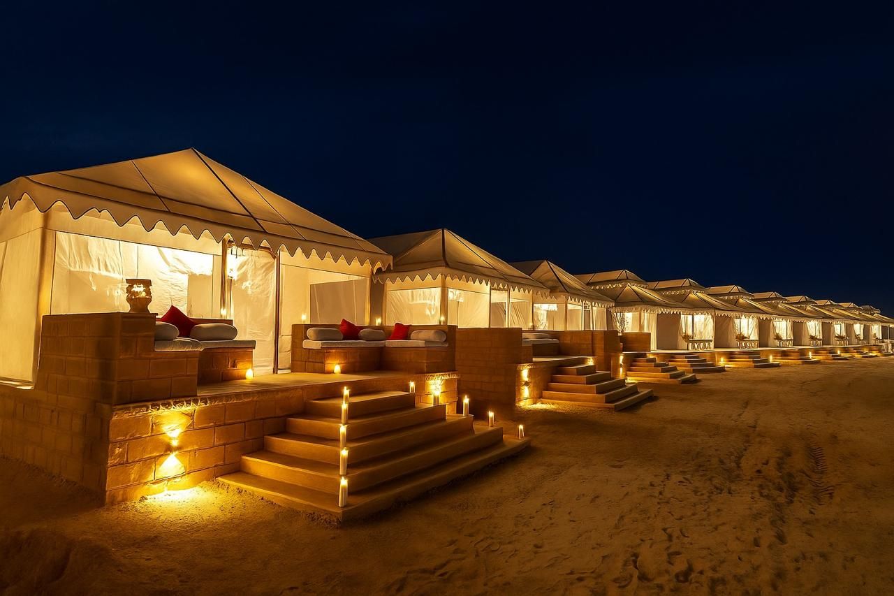 A row of tents with steps leading to the entrance, each with a small table and seating area.