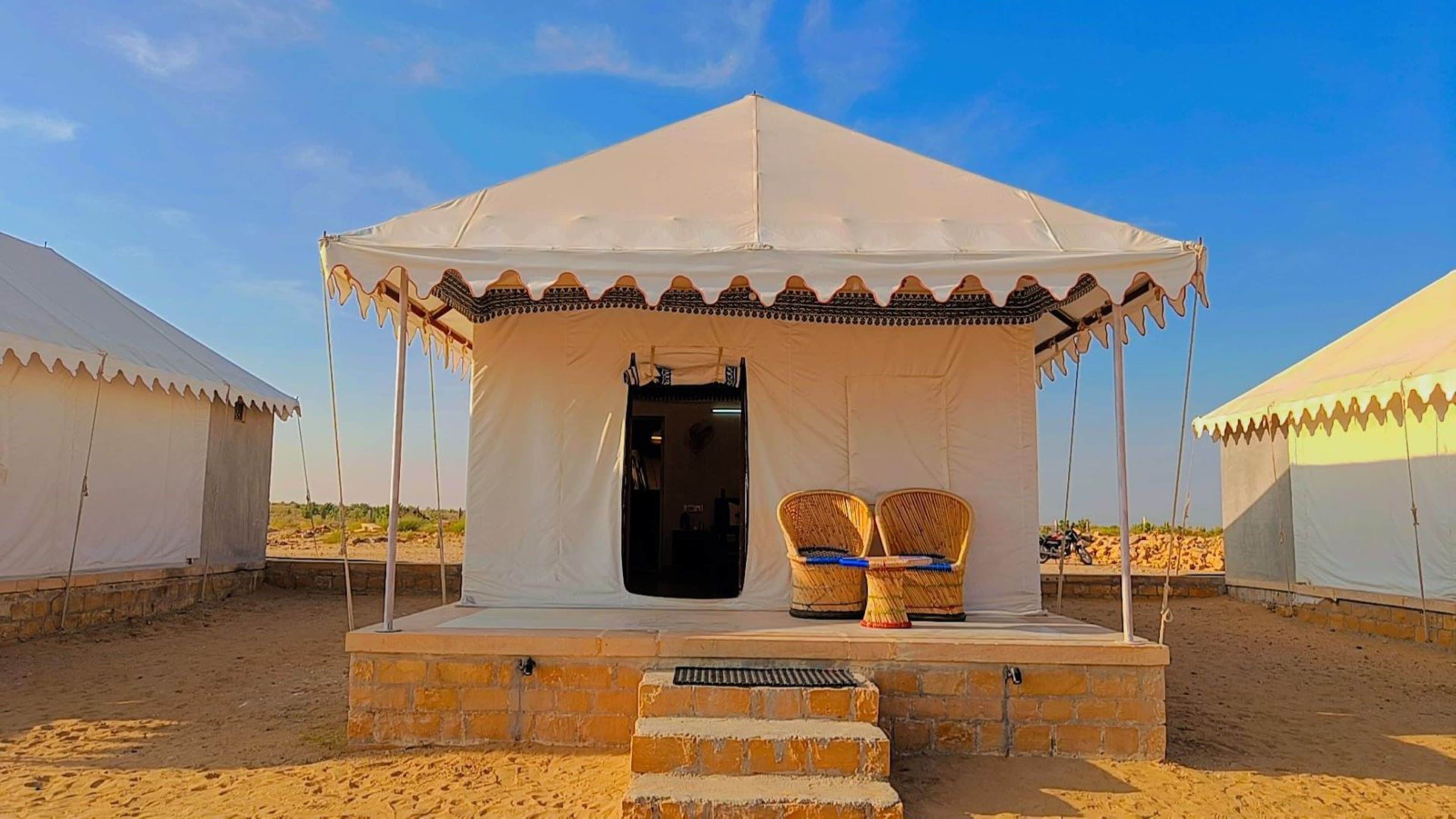 A tent with a covered entrance and two wicker chairs outside.