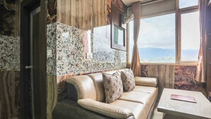 Una habitación con sofá, una mesa y ventana con vistas.