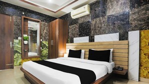 Una habitación de hotel moderna con una cama grande, cabecero de madera, paredes de mármol y un armario empotrado.