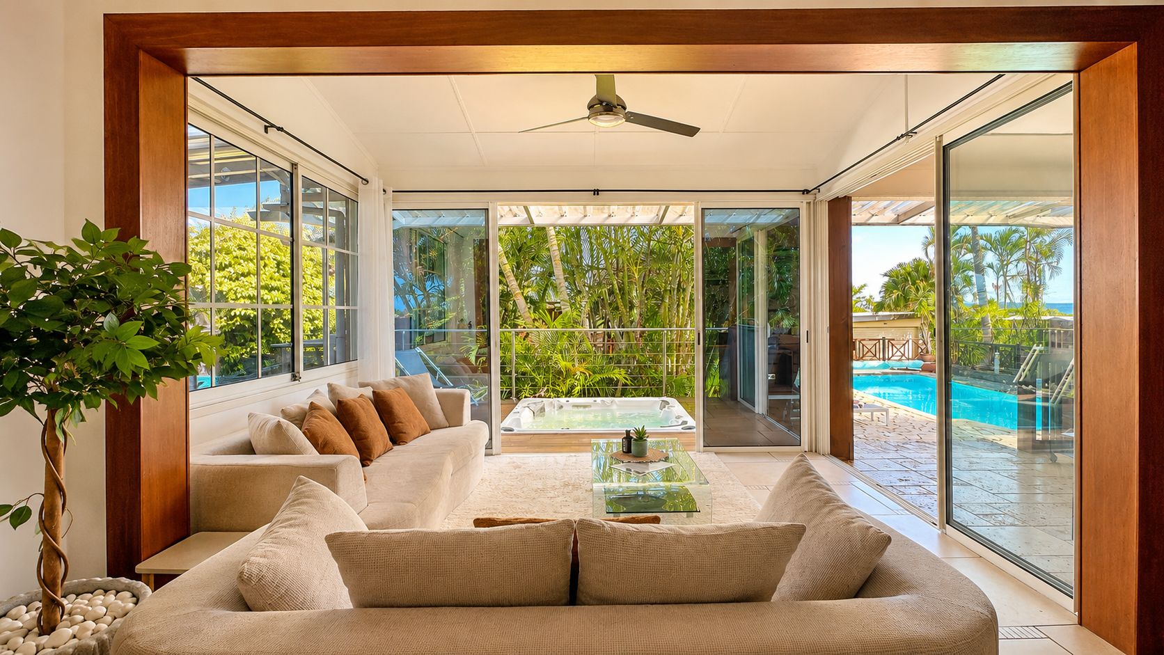 Un salon moderne avec un canapé, une table basse et une grande fenêtre donnant sur une piscine.