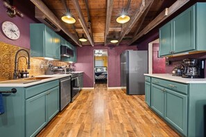 Una cocina con armarios azul turquesa, piso de madera y una isla central.