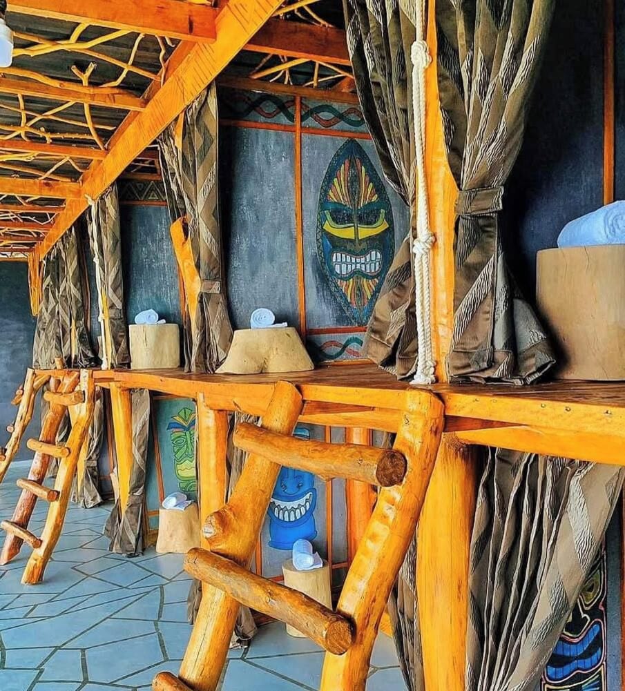 Een houten constructie met een schuin dak, mogelijk een bar of zithoek, met een decoratieve muur met een kleurrijk embleem.