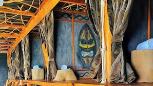 A wooden structure with a slanted roof, possibly a bar or seating area, with a decorative wall featuring a colorful emblem. - Dreamville (Ballaketuwa)