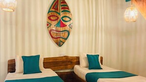 Quarto com duas camas de madeira, roupa de cama branca, almofadas verde-água e uma obra de arte colorida na parede.