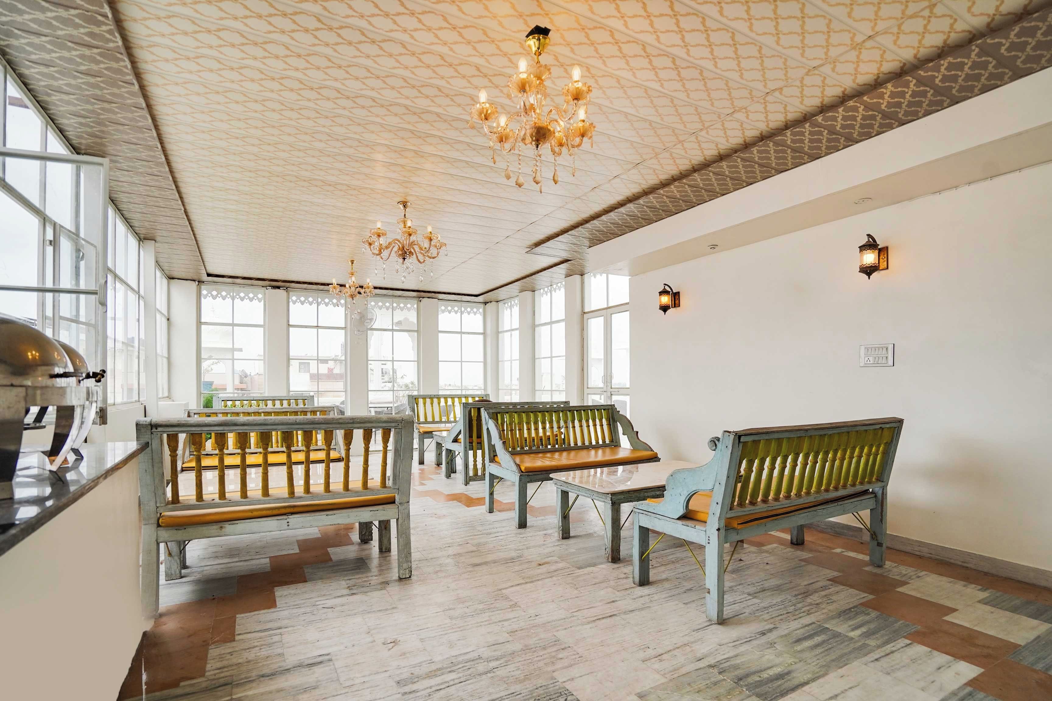 Um quarto amplo com vários bancos de madeira e um candelabro.