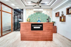 En receptionsdisk med et skilt, der viser 'TOWNHOUSE OAK', en loftsvifte og dekorative billeder på væggen.