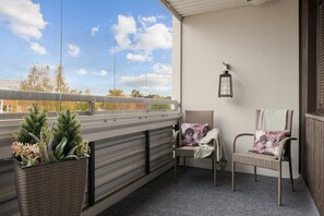 A balcony with wicker chairs, a potted plant, and a lantern. - Laponia | Colourful Nordic Home with Private Sauna (Rovaniemi)
