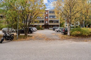 A parking area with cars and a motorcycle, surrounded by trees with autumn leaves. - Laponia | Colourful Nordic Home with Private Sauna (Rovaniemi)