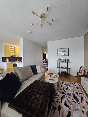 A modern living room with a sofa, a coffee table, and a unique ceiling light fixture. - Laponia | Colourful Nordic Home with Private Sauna (Rovaniemi)