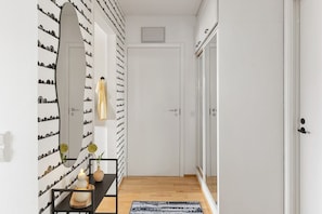 A hallway with a mirrored wall, a door, and a small table with a vase and candles. - Laponia | Colourful Nordic Home with Private Sauna (Rovaniemi)