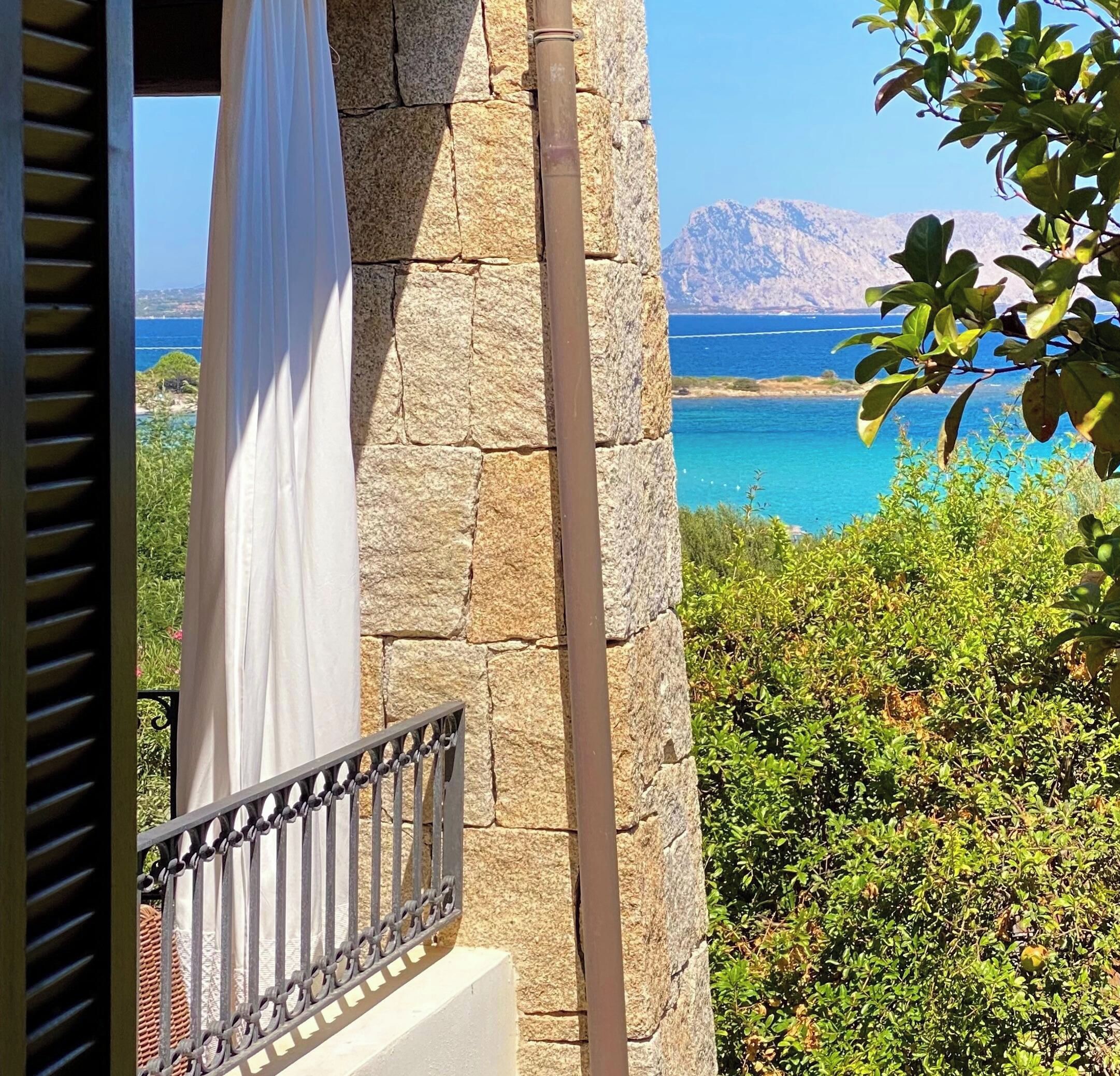A stone wall with a balcony overlooking a coastal landscape.