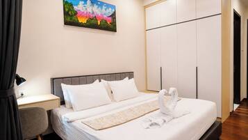 A hotel room with a bed, a desk, a chair, a wardrobe, and a painting on the wall.