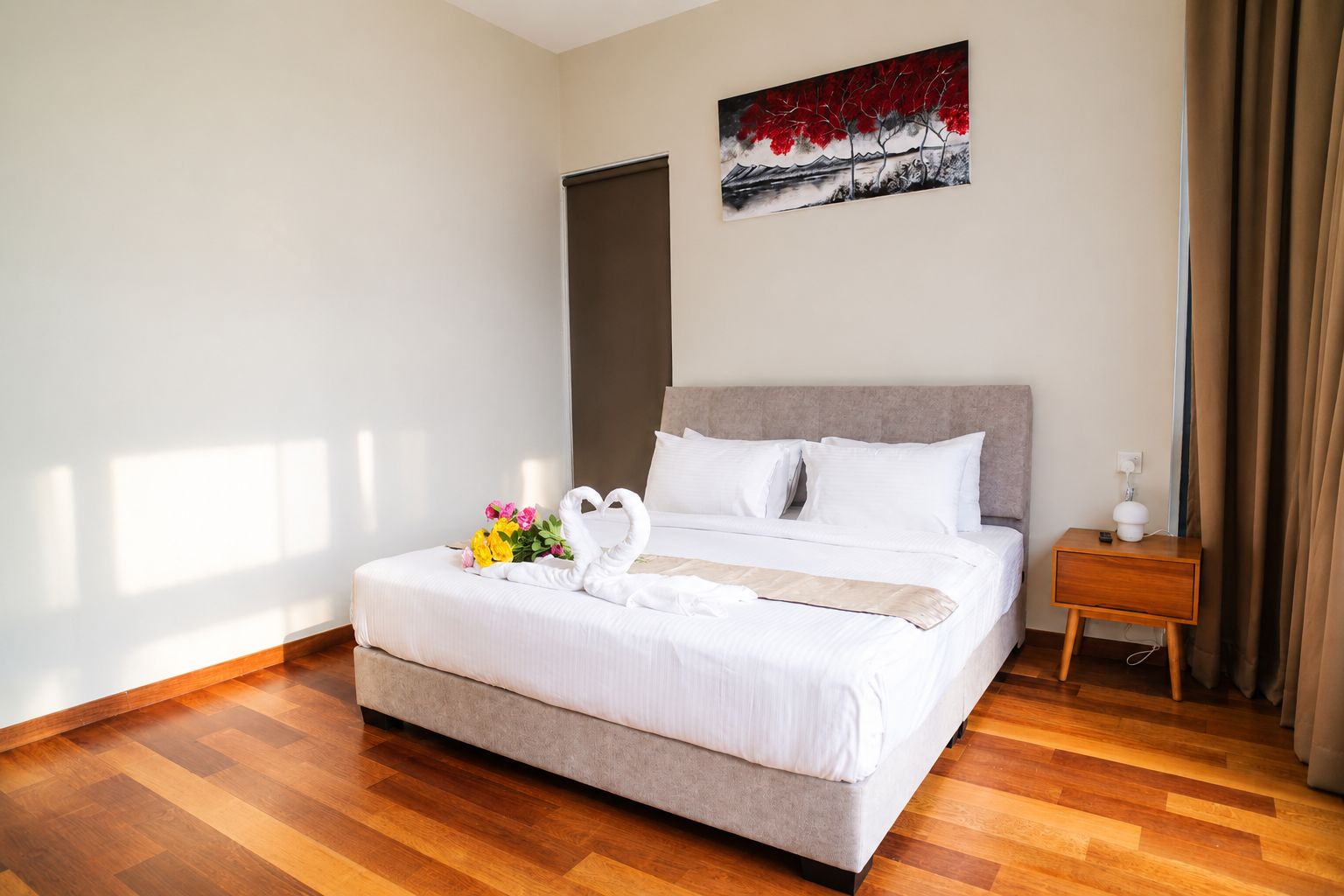 Una habitación de hotel con una cama, una mesita de noche, un cuadro y un ramo de flores.