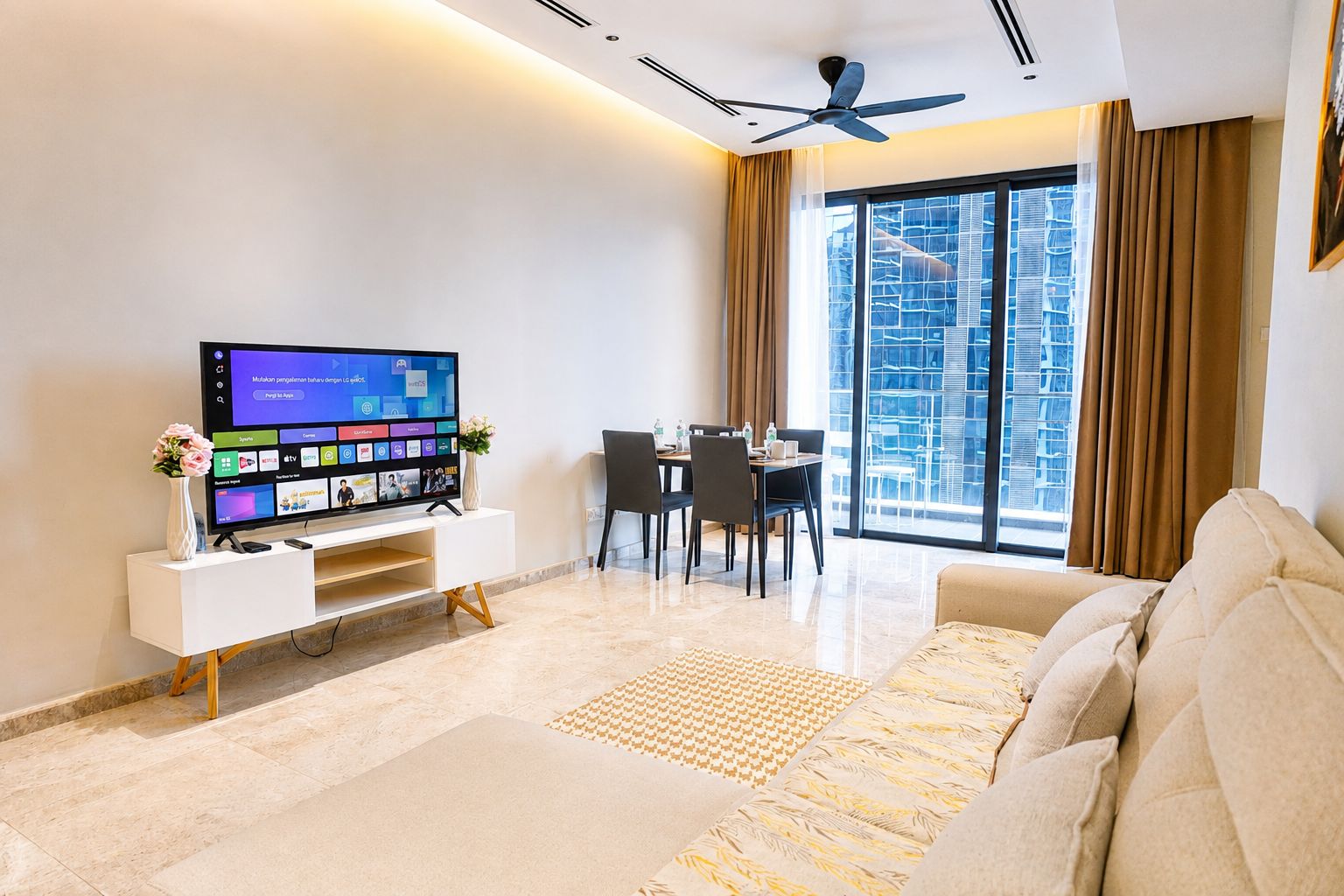 Una sala de estar moderna con un televisor de pantalla plana, un comedor y un ventanal con vistas a la ciudad.