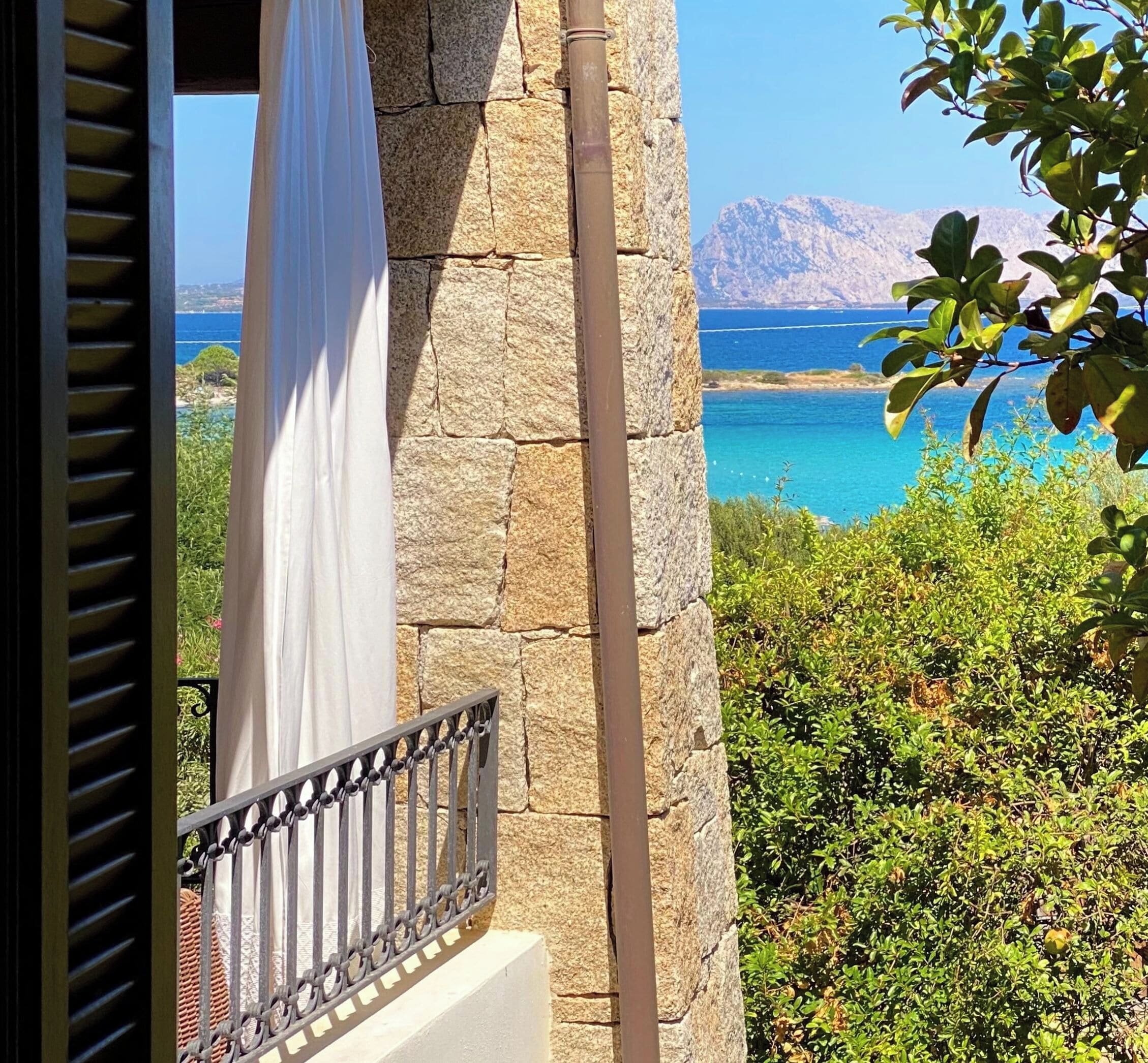A stone wall with a balcony overlooking a coastal landscape.