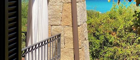 A stone wall with a balcony overlooking a coastal landscape.