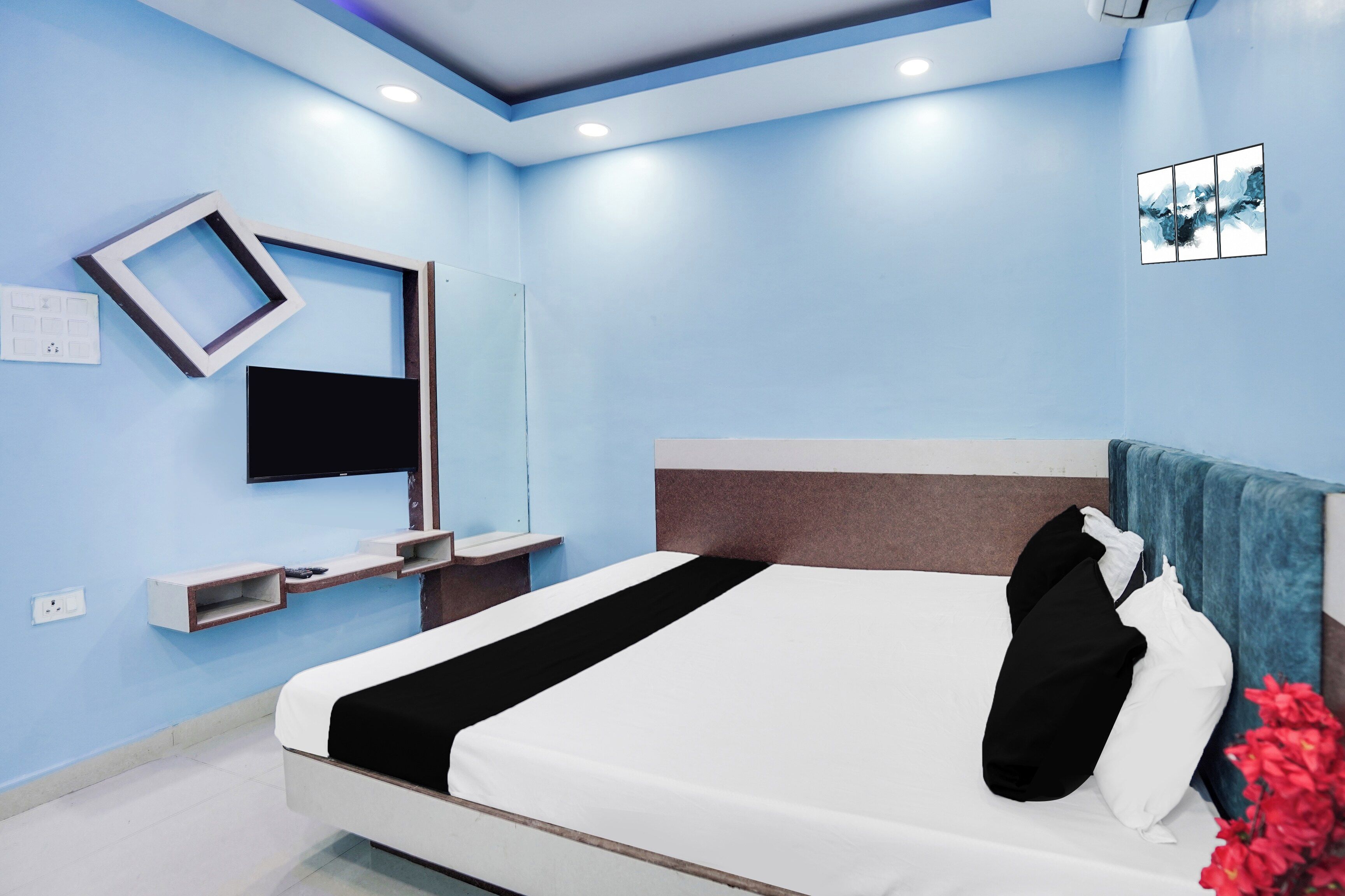 A modern bedroom with a bed, a mounted TV, and a wall-mounted shelf.