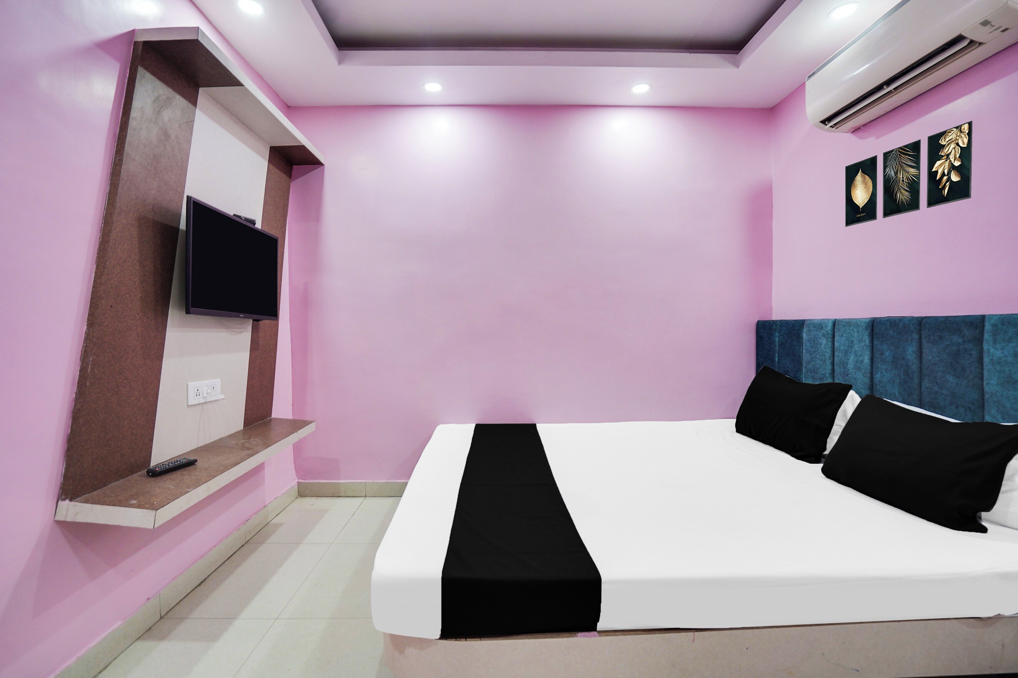 Un dormitorio con cama, televisor montado en la pared y aire acondicionado en el techo.
