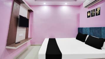 Un dormitorio con cama, televisor montado en la pared y aire acondicionado en el techo.