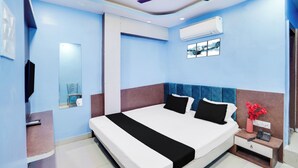 A hotel room with a large bed, a ceiling fan, an air conditioning unit, a small bedside table with a phone, and a mirror on the wall. - Townhouse Butler Road Near Maripur Chowk (Muzaffarpur)