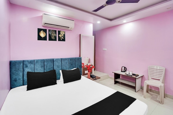 A modern bedroom with a large bed, a blue headboard, an air conditioning unit, and a ceiling fan.
