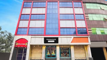 Un edificio de varios pisos con un letrero que dice 'TOWNHOUSE' y un cartel de 'BIENVENIDOS' sobre la entrada.
