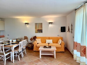 A living room with a sofa, a coffee table, a dining table with chairs, and a painting on the wall. - Villa Elena Ground Floor – Sea Front and Garden (San Teodoro)
